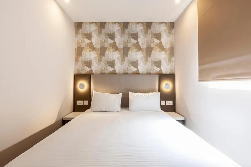 Lit double avec oreillers blancs dans une chambre lumineuse.