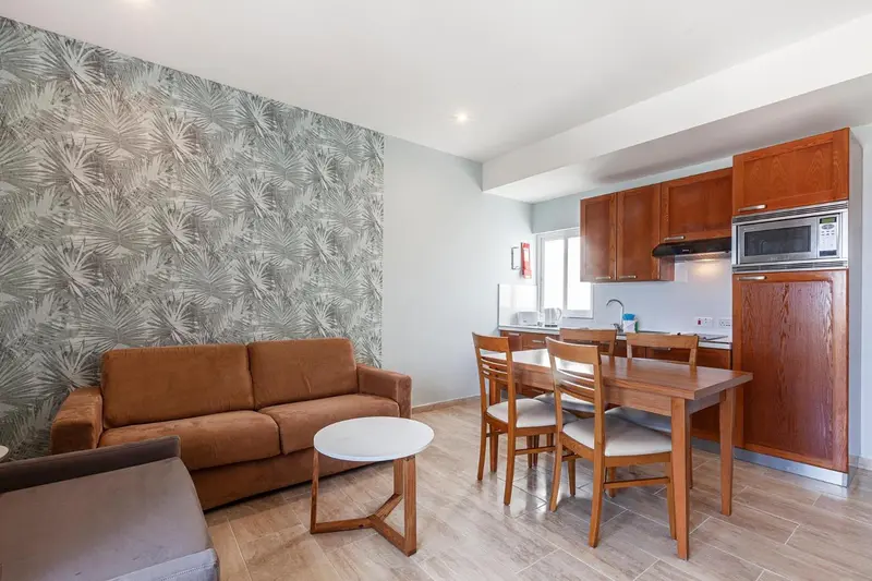 Espace de vie avec canapé marron et coin repas en bois.