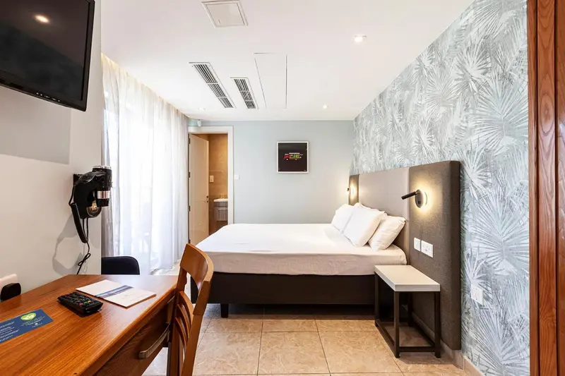 Une chambre lumineuse avec un grand lit et un bureau en bois.