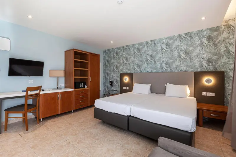 Chambre lumineuse avec un grand lit et un bureau en bois.