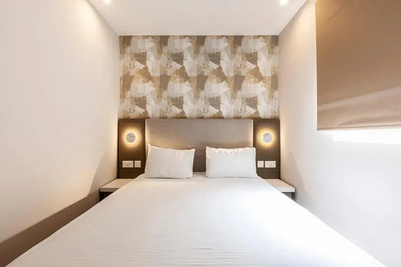 Une chambre avec un grand lit blanc et un mur décoratif.