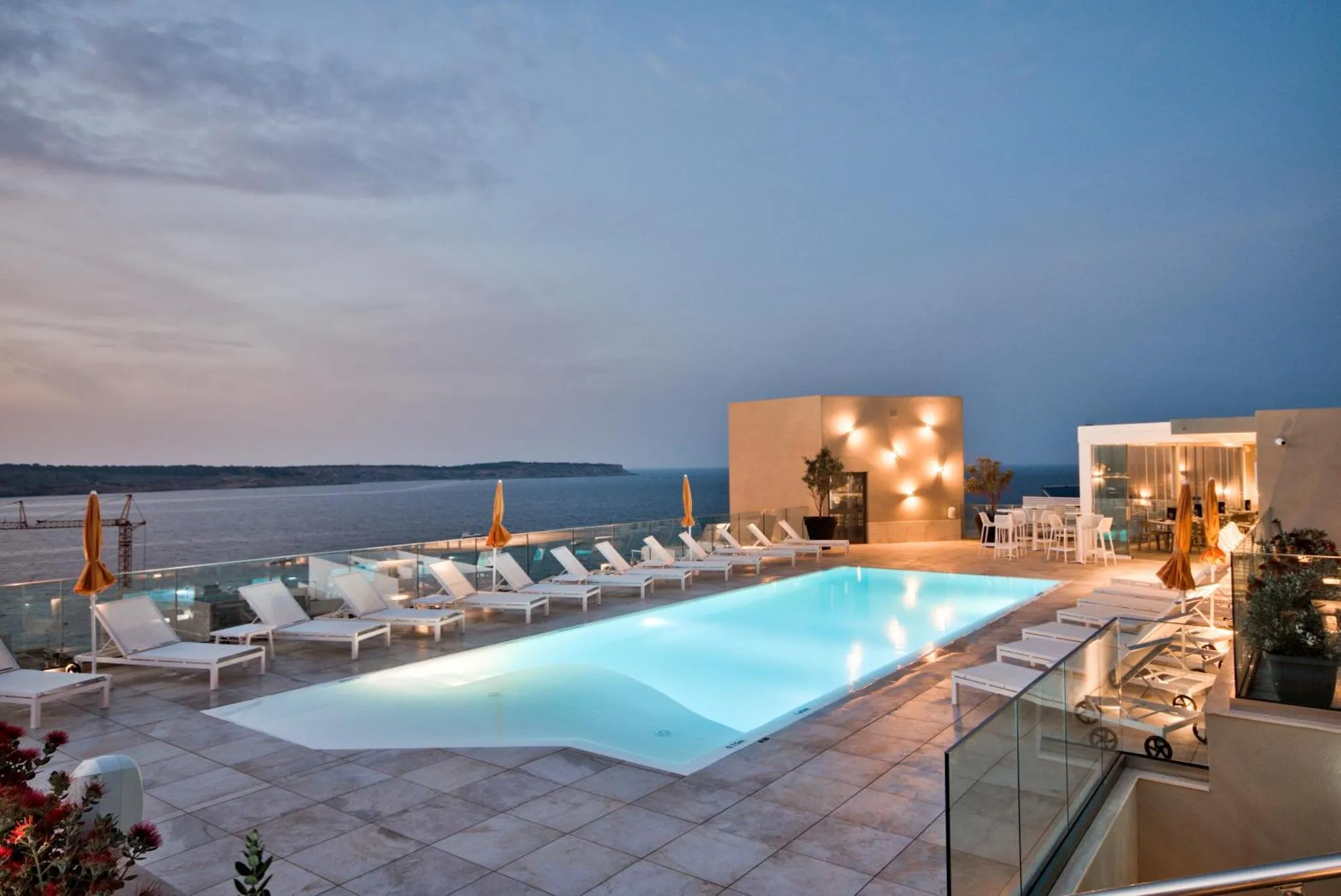 Terrasse avec piscine et vue sur la mer au crépuscule.