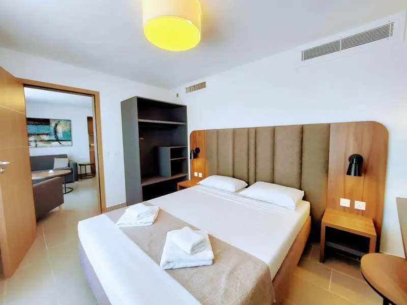 Une chambre lumineuse avec un grand lit et un espace salon.