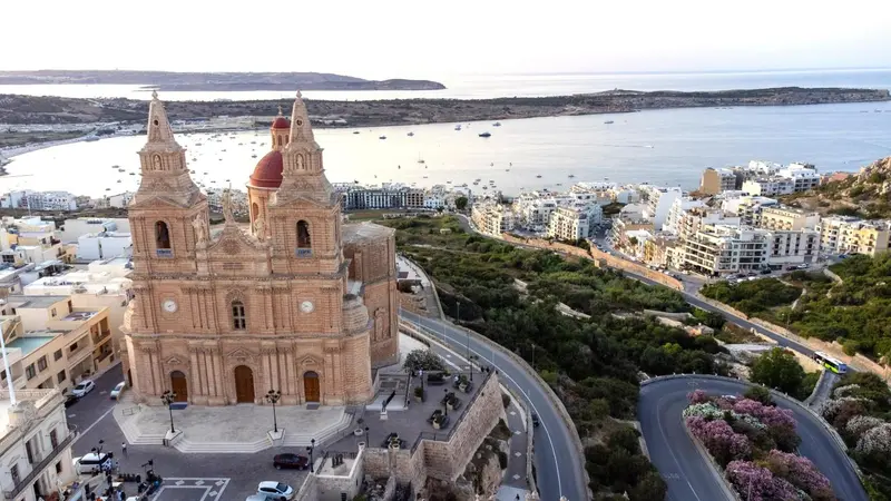 Vue aérienne d'une église baroque et d'une ville côtière ensoleillée.