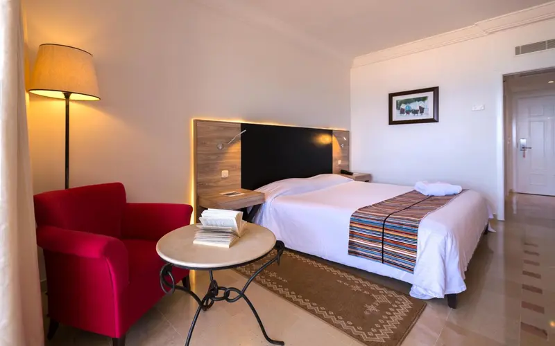 Une chambre d'hotel avec un lit et un fauteuil rouge.