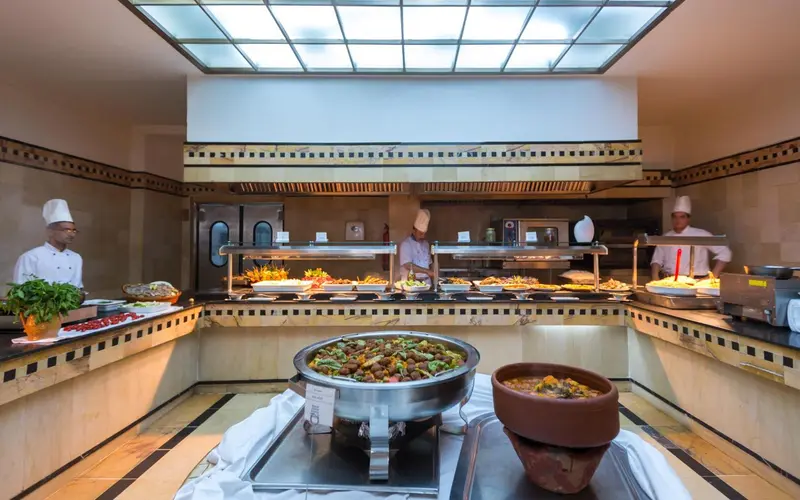 Un buffet propose une variété de plats chauds et froids dans un espace lumineux.