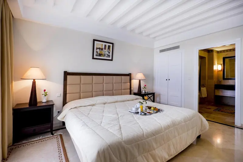 Une chambre lumineuse avec un grand lit recouvert d'une courtepointe.
