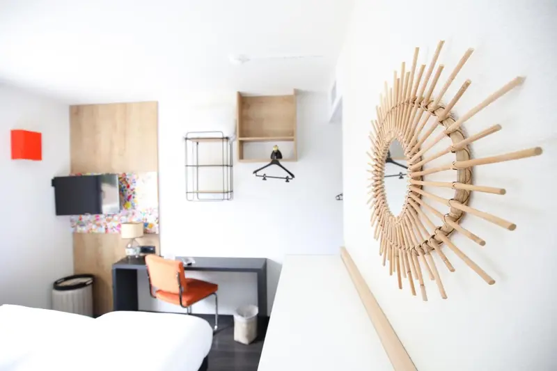 Une chambre lumineuse avec un bureau et une décoration murale en forme de soleil.