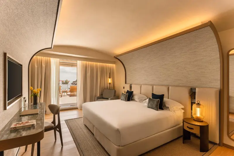 Une chambre lumineuse avec un grand lit et un accès à un balcon.