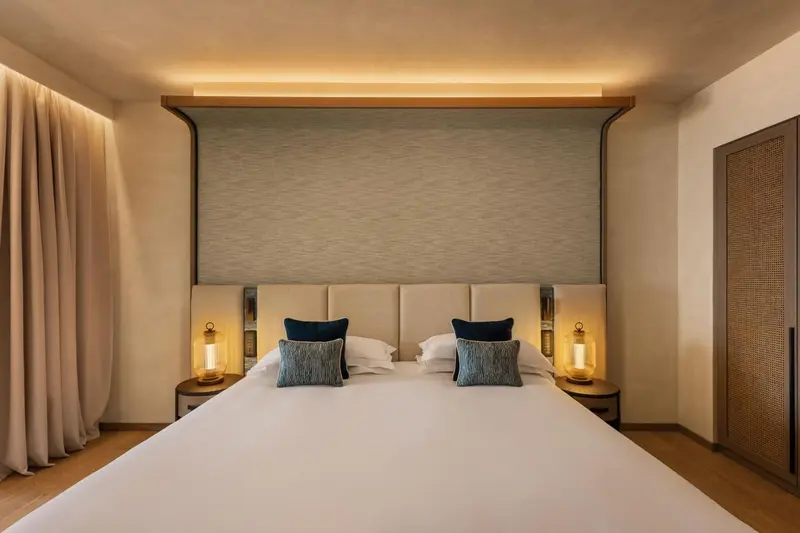 Une chambre lumineuse avec un grand lit et des coussins décoratifs.