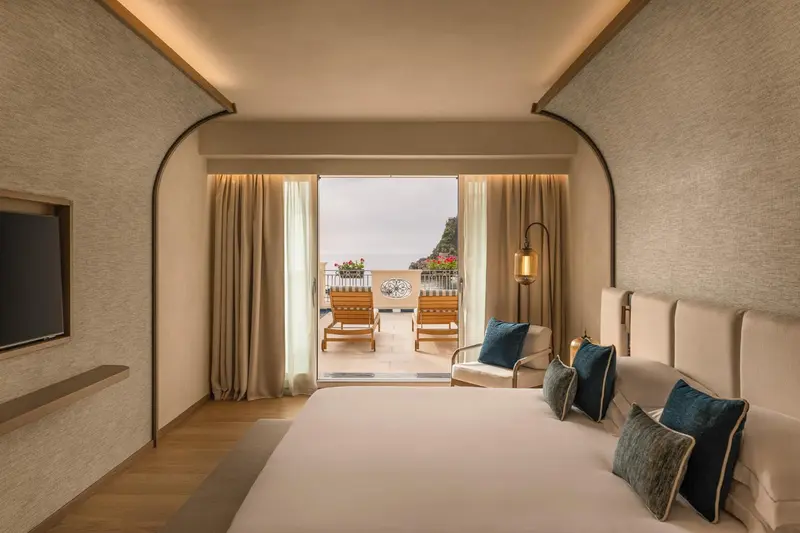 Une chambre lumineuse s'ouvre sur une terrasse avec vue sur la mer.