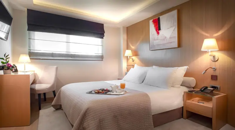 Une chambre lumineuse avec un lit double et un plateau de petit-déjeuner.