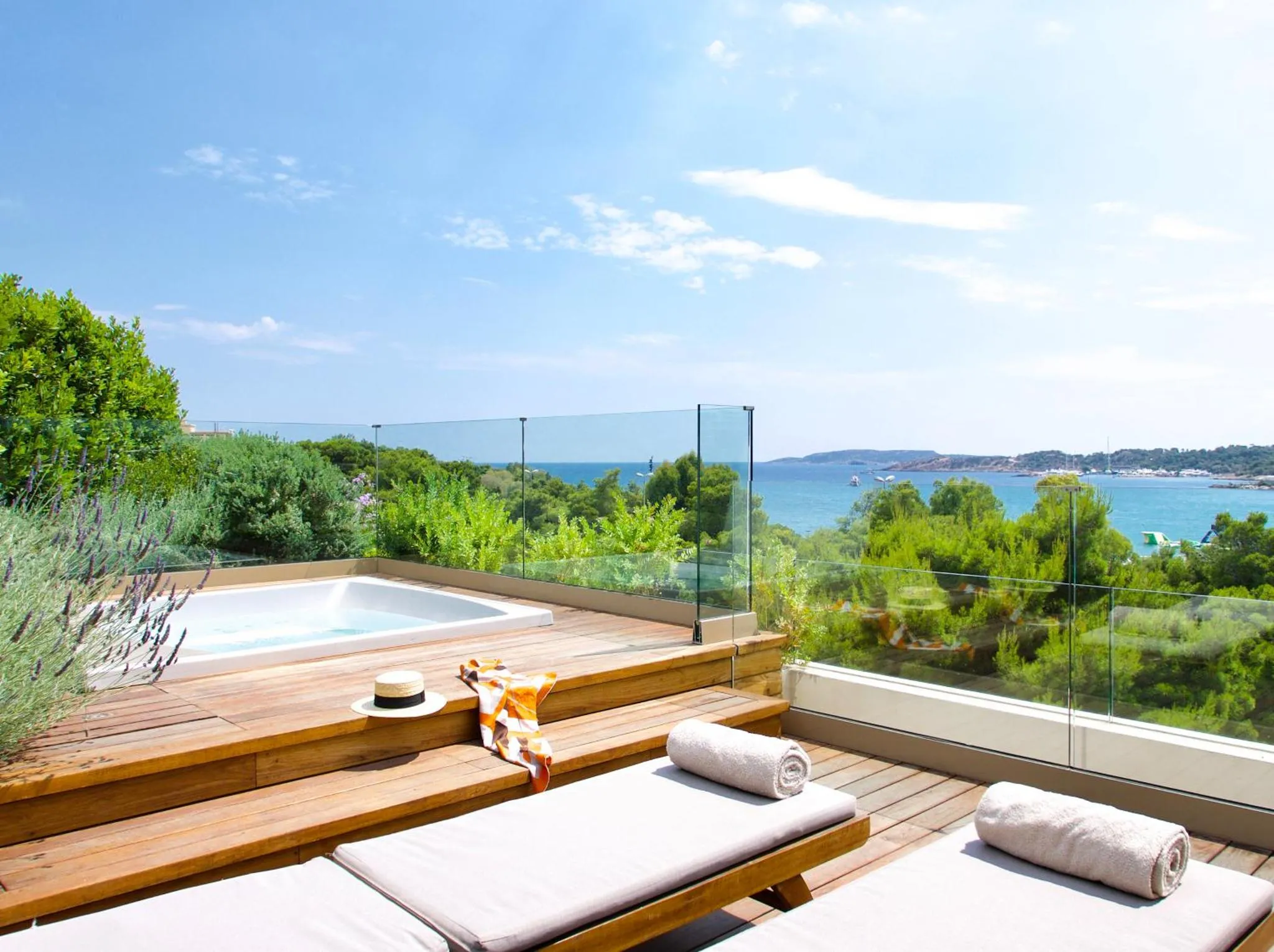 Terrasse en bois avec jacuzzi et transats offrant une vue sur la mer.