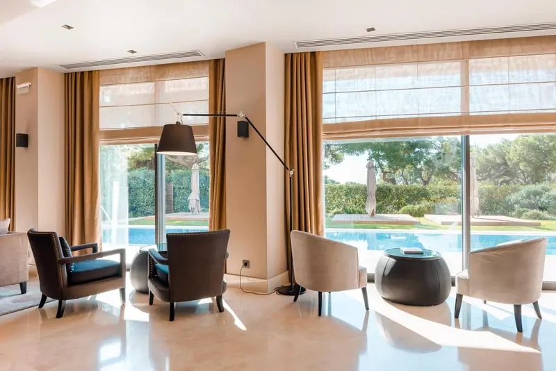 Un espace de détente intérieur avec des fauteuils et une vue sur une piscine.