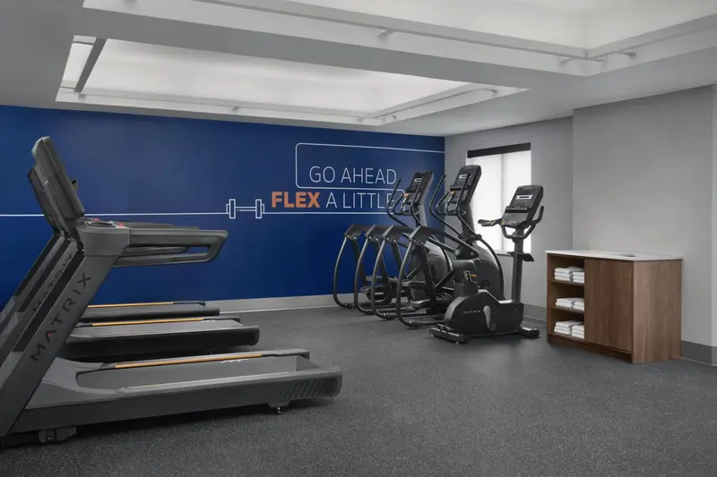 Une salle de sport lumineuse avec plusieurs appareils de cardio.