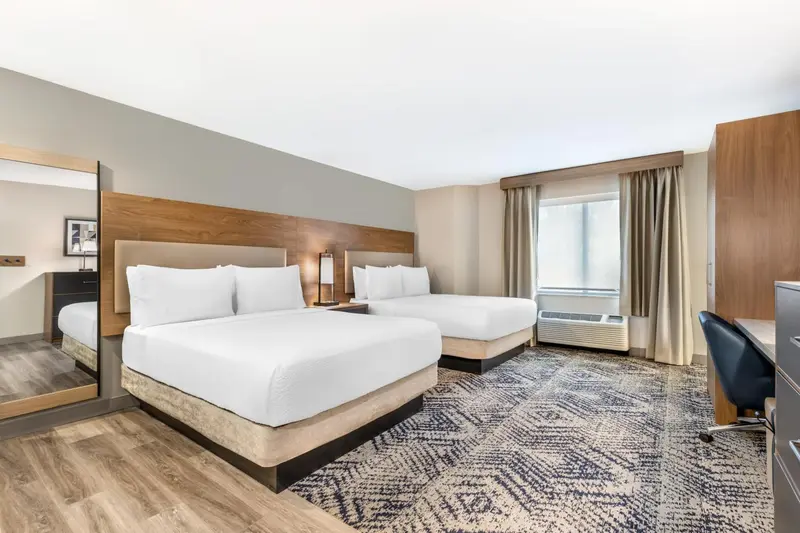 Chambre avec deux lits et bureau près de la fenêtre.