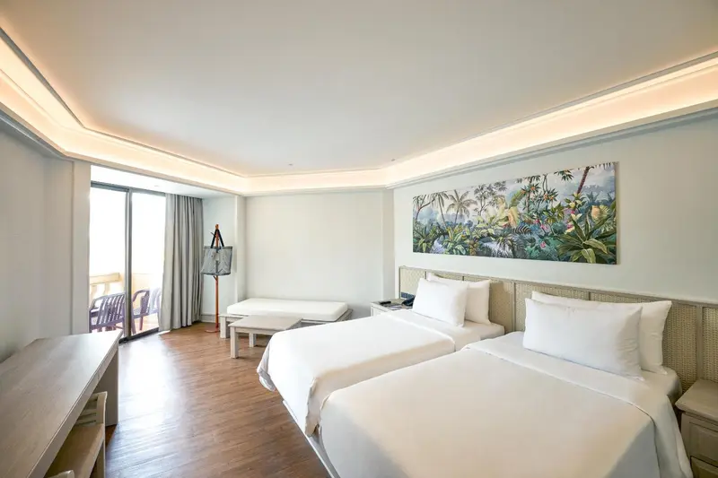 Une chambre lumineuse avec deux lits simples et un accès à un balcon.