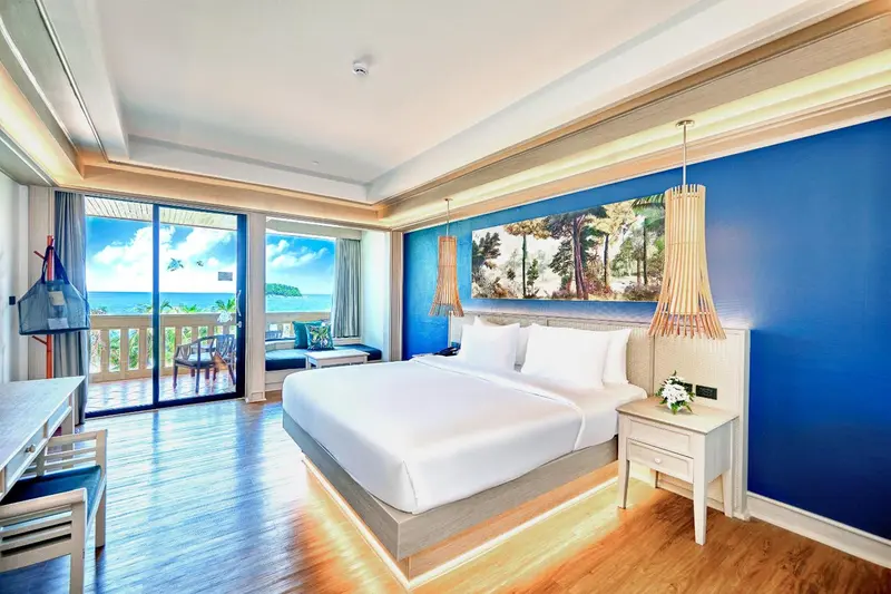 Une chambre lumineuse avec un grand lit et un accès à une terrasse offrant une vue sur la mer.