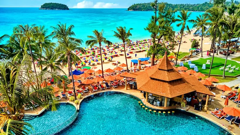 Vue aérienne d'une plage bordée de palmiers et d'une piscine avec un bar.