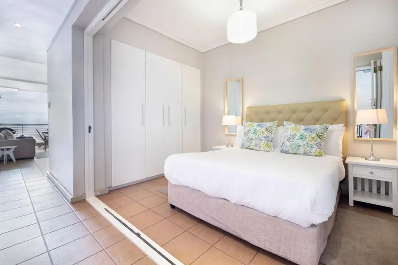 Une chambre lumineuse avec un grand lit et des rangements.