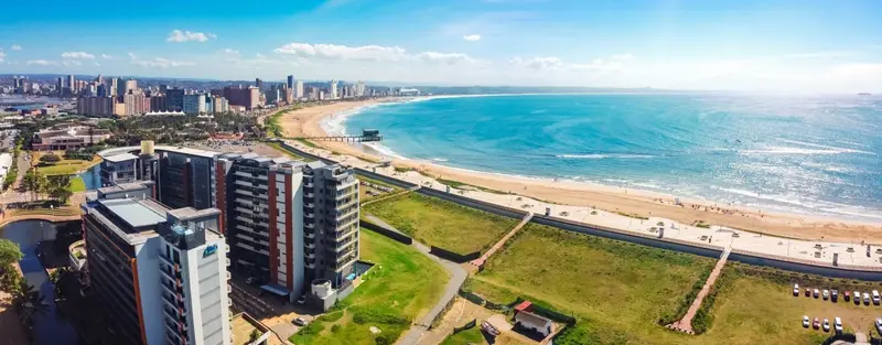 Vue aérienne d'une plage de sable fin bordée de bâtiments et d'une ville en arrière-plan.