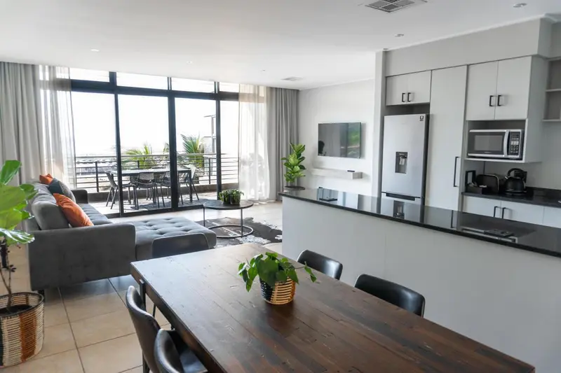 Espace de vie lumineux avec cuisine équipée et accès à une terrasse.