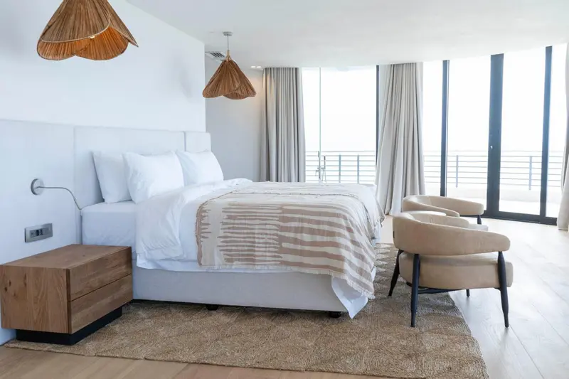 Une chambre lumineuse avec un grand lit et un accès à un balcon.