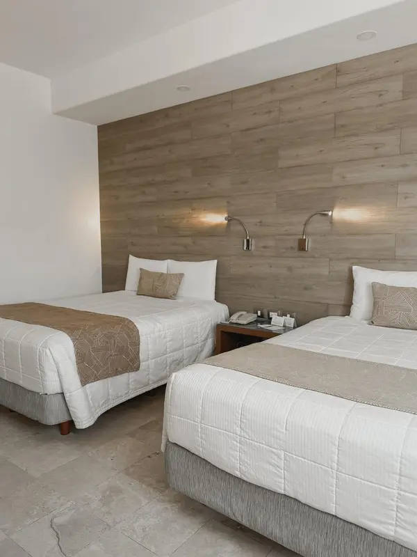 Une chambre d'hôtel avec deux lits simples et un mur en bois.