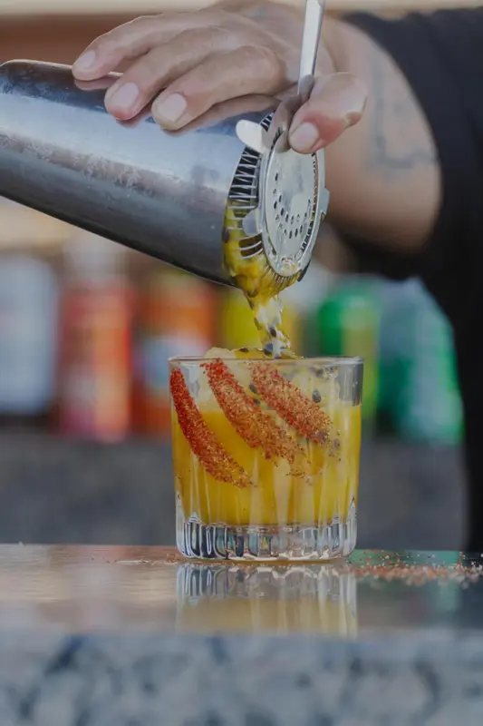 Un cocktail jaune est préparé et versé dans un verre décoré.