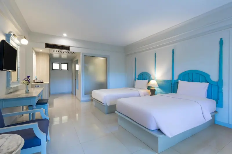 Chambre lumineuse avec deux lits simples et décoration bleue.