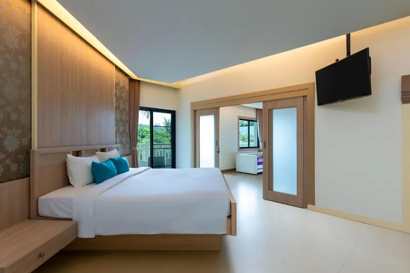 Une chambre lumineuse avec un grand lit et une télévision murale.