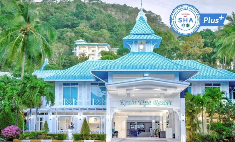 Bâtiment bleu à toit pointu avec végétation tropicale environnante.