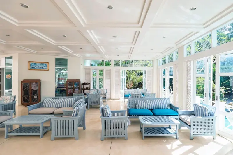 Espace de détente lumineux avec mobilier en rotin et vue sur l'extérieur.