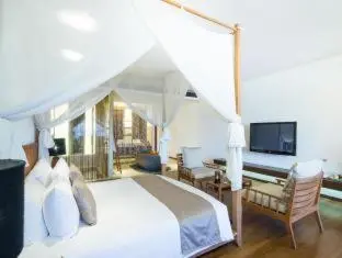 Une chambre lumineuse avec un grand lit à baldaquin et un coin salon.