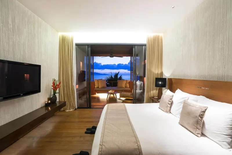 Chambre lumineuse avec un grand lit et vue sur la mer.