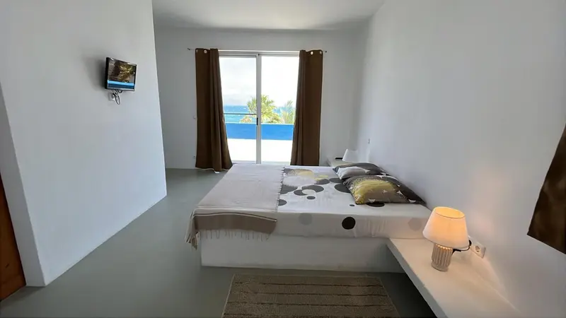 Une chambre lumineuse avec un grand lit et un accès à une terrasse.