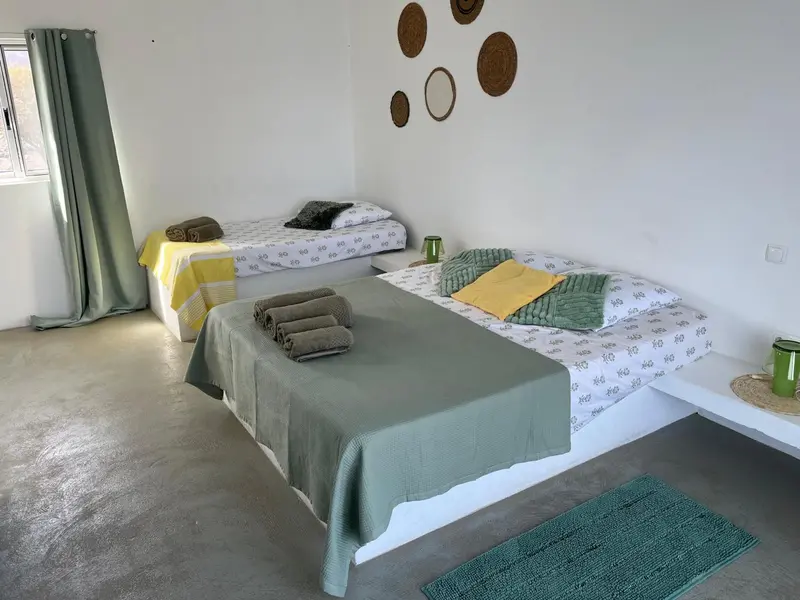 Une chambre lumineuse avec deux lits simples et une décoration murale.