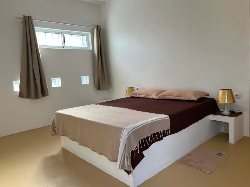 Une chambre lumineuse avec un lit recouvert d'une couverture et de coussins.
