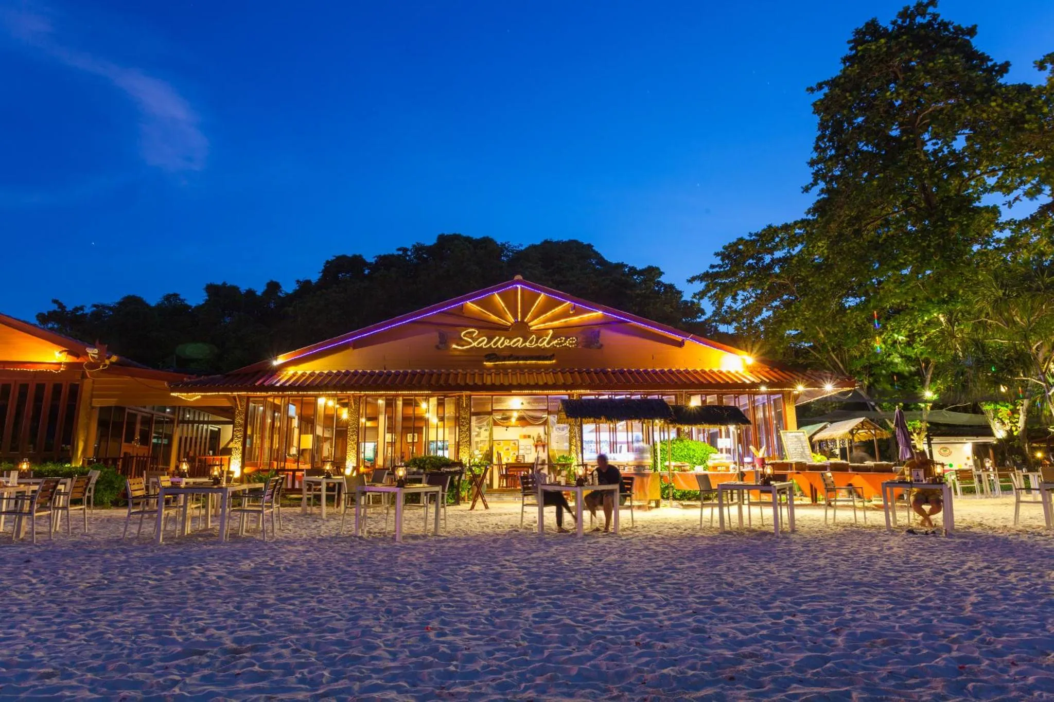 Restaurant en bord de mer illuminé au crépuscule.