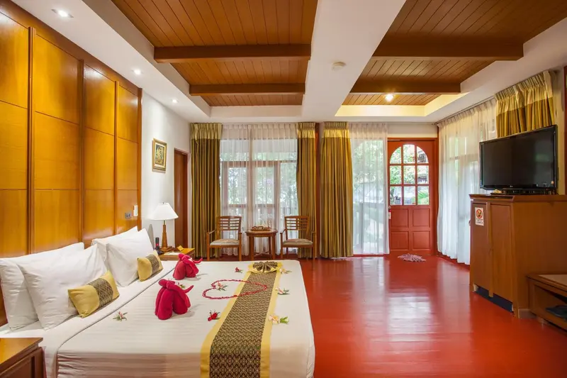 Chambre lumineuse avec un grand lit décoré de fleurs et une vue sur l'extérieur.