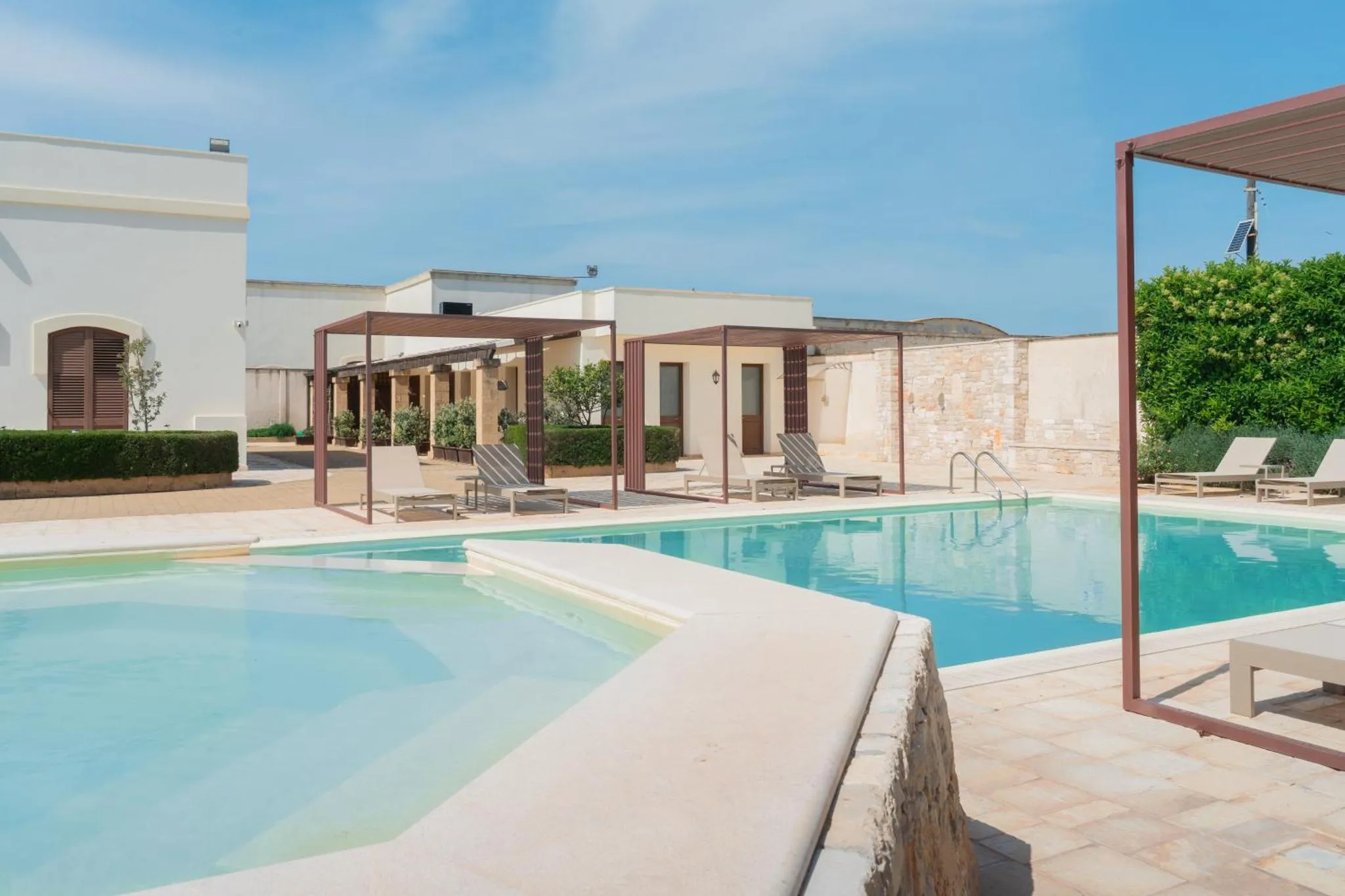 Piscine rectangulaire avec transats et pergola ombragée.