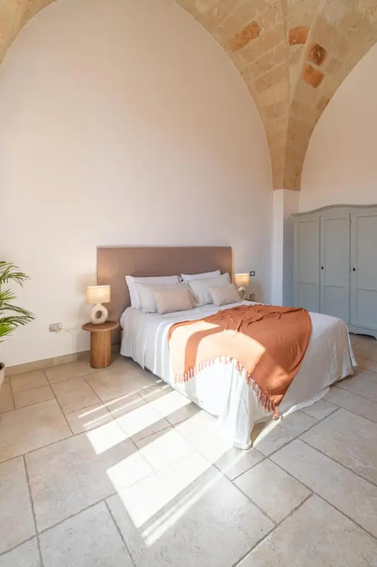 Une chambre lumineuse avec un grand lit recouvert d'une couverture.