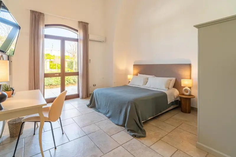 Une chambre lumineuse avec un lit fait et un bureau près d'une fenêtre.