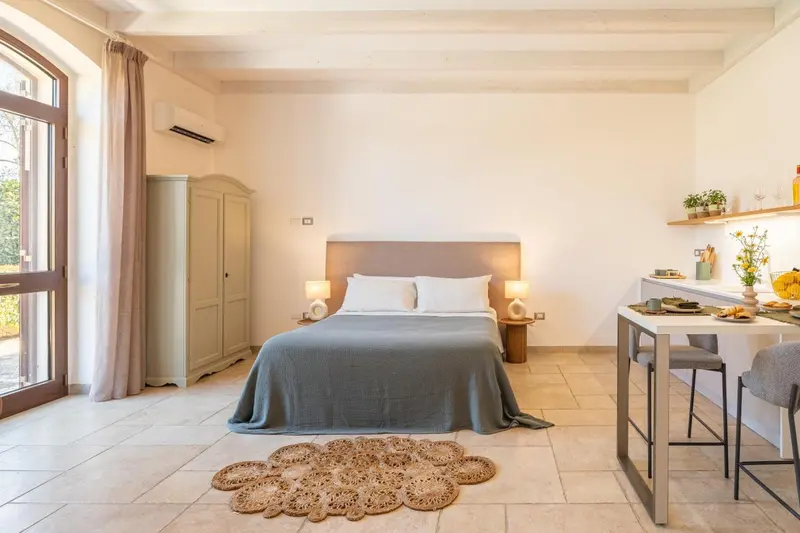 Une chambre lumineuse avec un lit double et un coin repas.