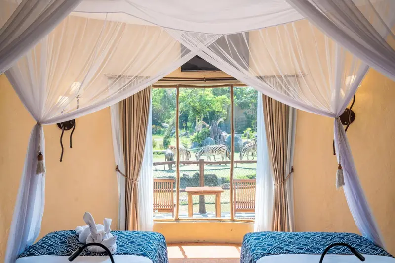 Lit à baldaquin dans une chambre avec vue sur une savane.