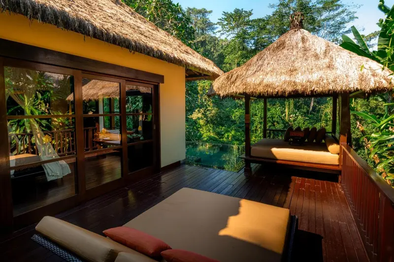 Terrasse en bois avec mobilier de relaxation et végétation luxuriante.
