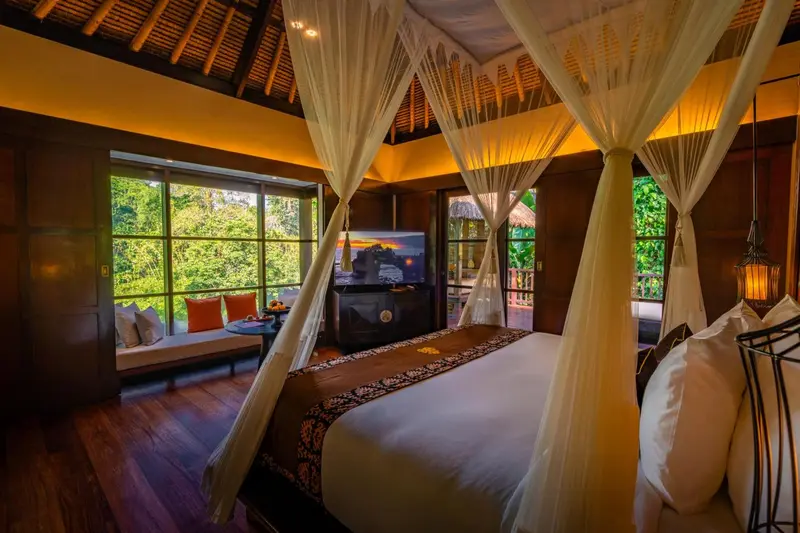 Une chambre avec un grand lit à baldaquin donnant sur une végétation luxuriante.