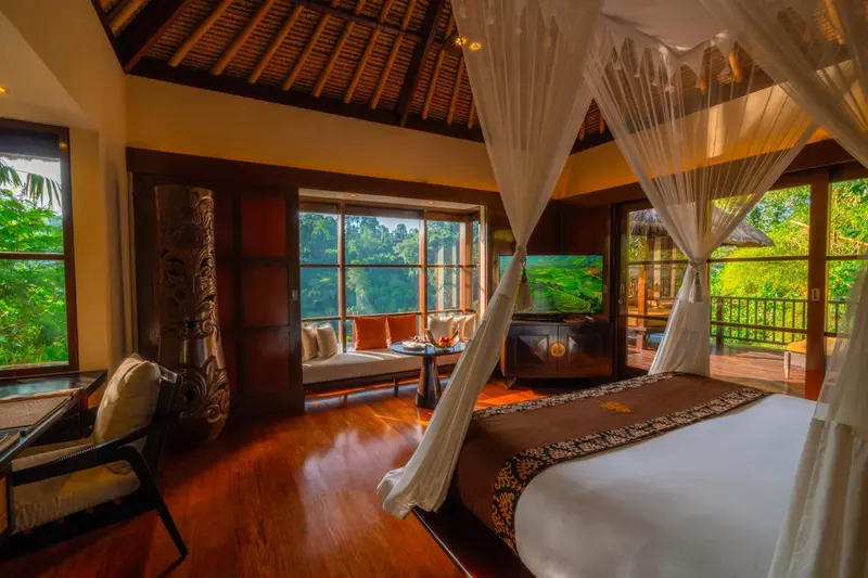 Une chambre spacieuse avec un lit à baldaquin donnant sur une végétation luxuriante.