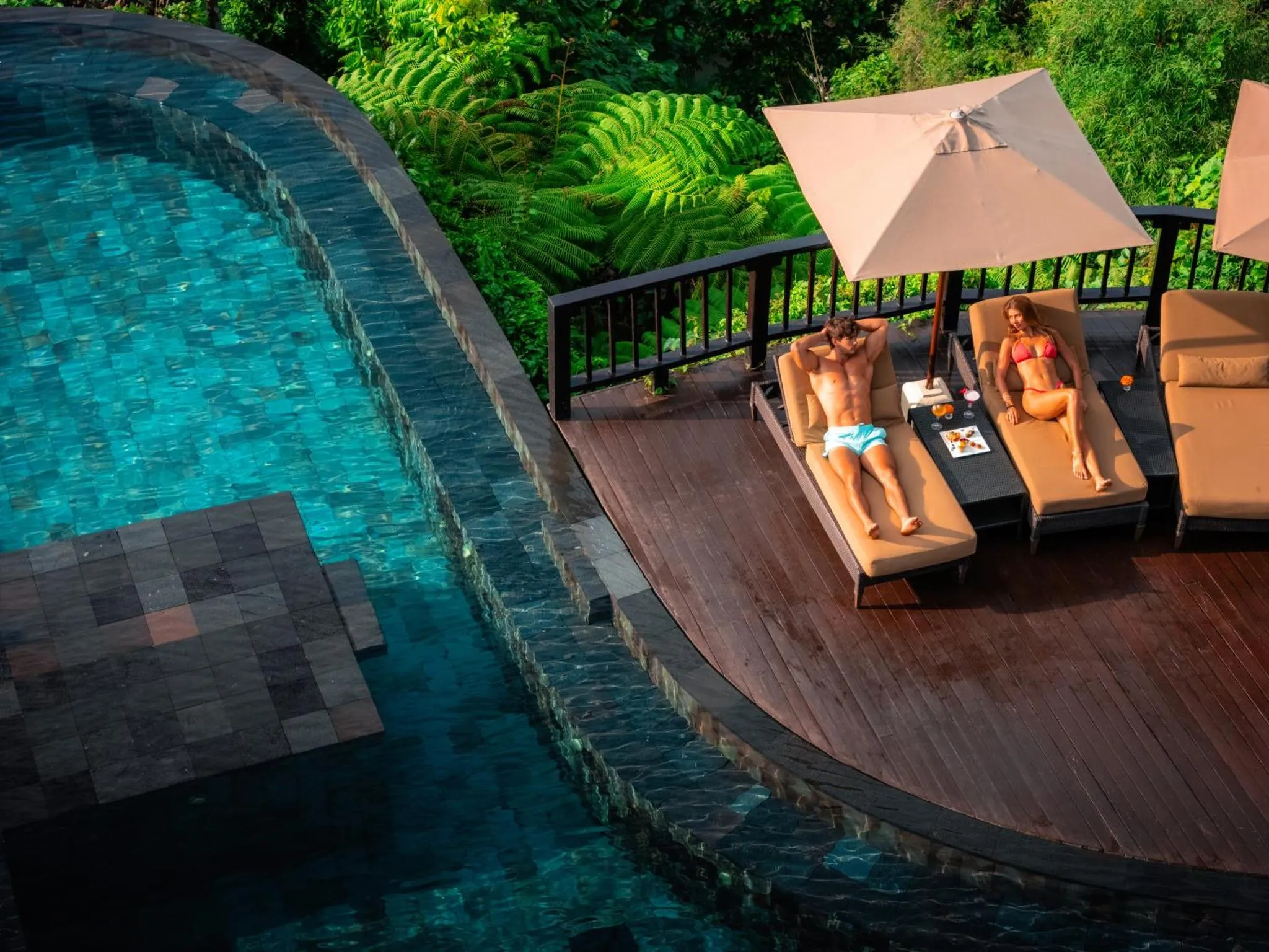 Un couple se relaxe sur des transats au bord d'une piscine à débordement.
