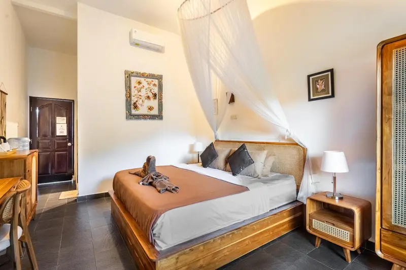 Une chambre lumineuse avec un grand lit à baldaquin et une commode en bois.